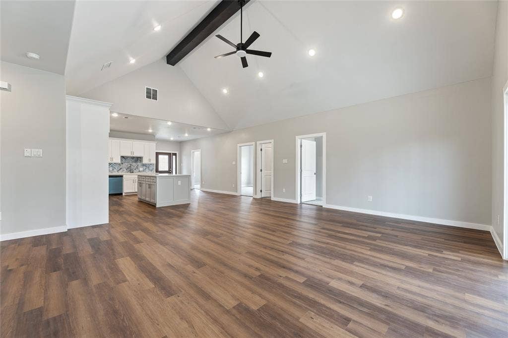 1242 Seminole Drive, Dallas, TX 75217 Open-concept interior featuring a vaulted ceiling, exposed structural beam, wood-finish flooring, recessed lighting, and a central kitchen island