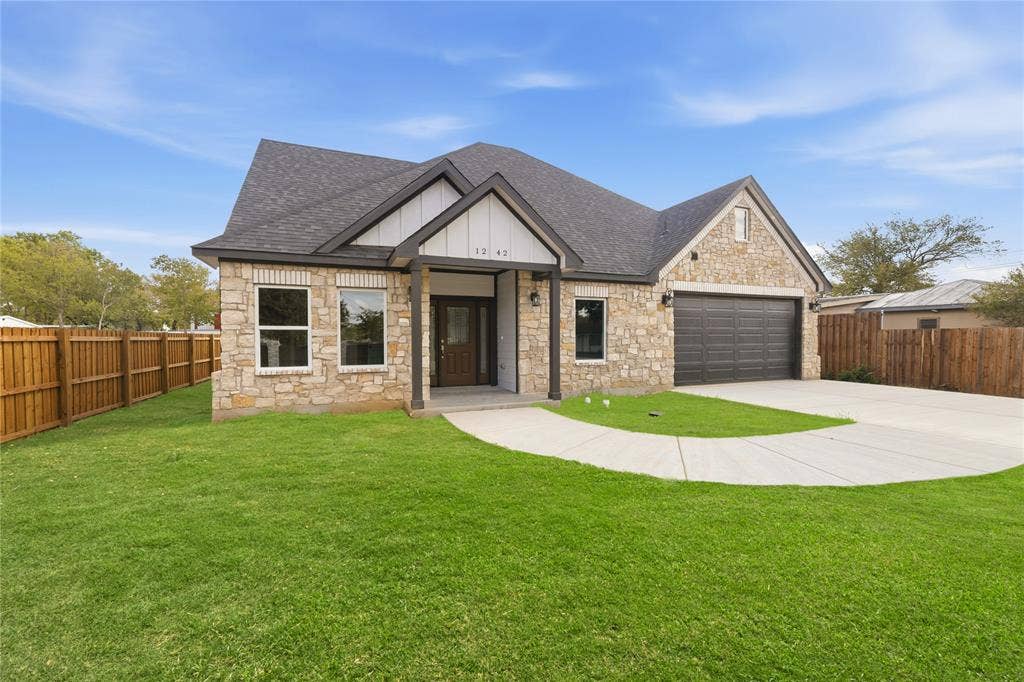 1242 Seminole Drive, Dallas, TX 75217 Single-story exterior featuring a stone facade, gabled roofline with peak detailing, dark-toned garage door, and covered entryway
