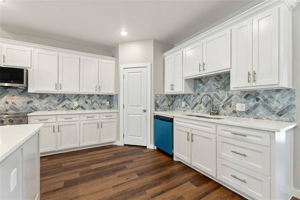 1242 Seminole Drive, Dallas, TX 75217 Kitchen featuring white shaker-style cabinetry, herringbone-pattern tile backsplash, wood-finish flooring, stone-surface countertops, and brushed nickel hardware