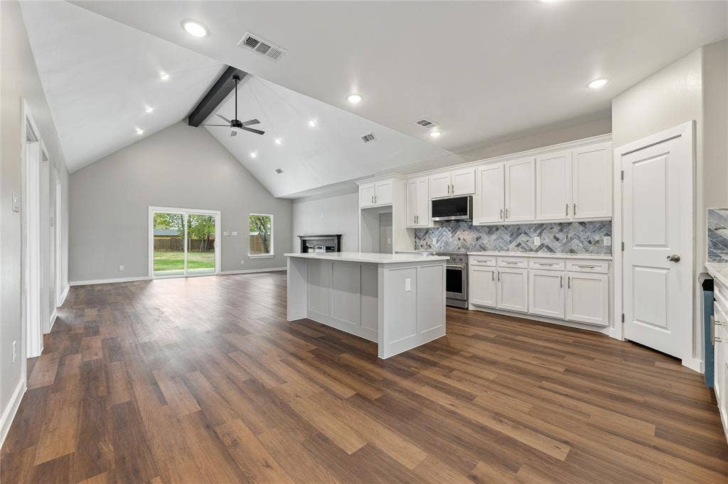 1242 Seminole Drive, Dallas, TX 75217 Vaulted ceilings, wood-finish flooring, central kitchen island with stone-finish countertop, herringbone-pattern tile backsplash, and recessed lighting