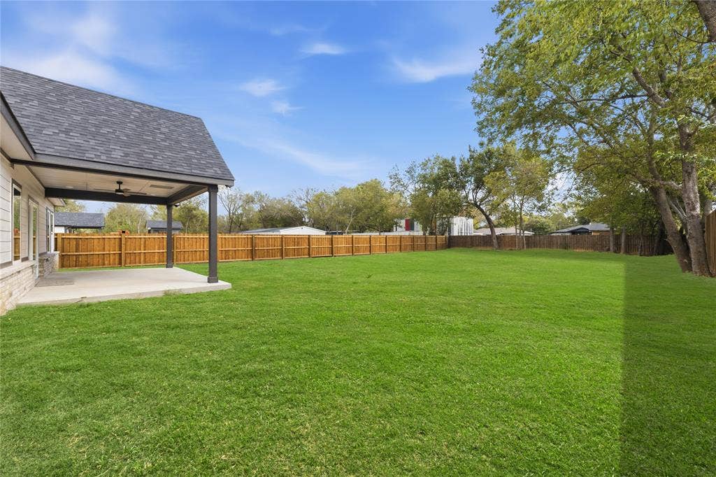 1242 Seminole Drive, Dallas, TX 75217 Expansive backyard featuring a covered patio, concrete flooring, a ceiling fan, and perimeter wood fencing