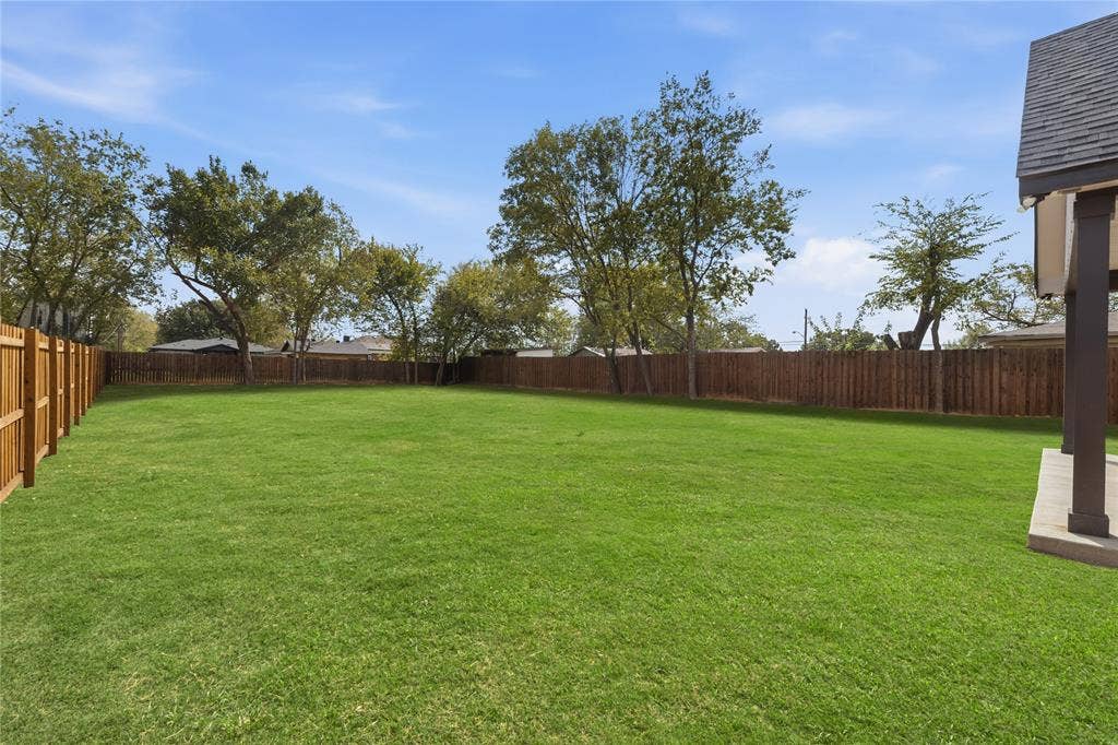 1242 Seminole Drive, Dallas, TX 75217 Expansive backyard featuring a large grass lawn, perimeter wood fencing, and mature trees