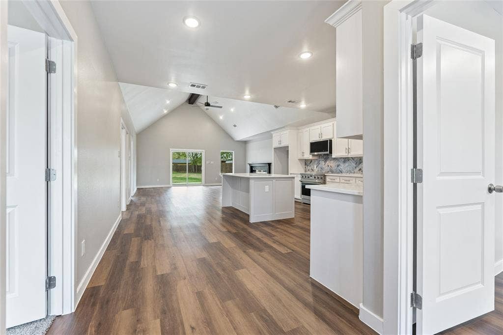 1242 Seminole Drive, Dallas, TX 75217 Open-concept floor plan featuring vaulted ceilings, wood-finish flooring, a central kitchen island, and recessed lighting