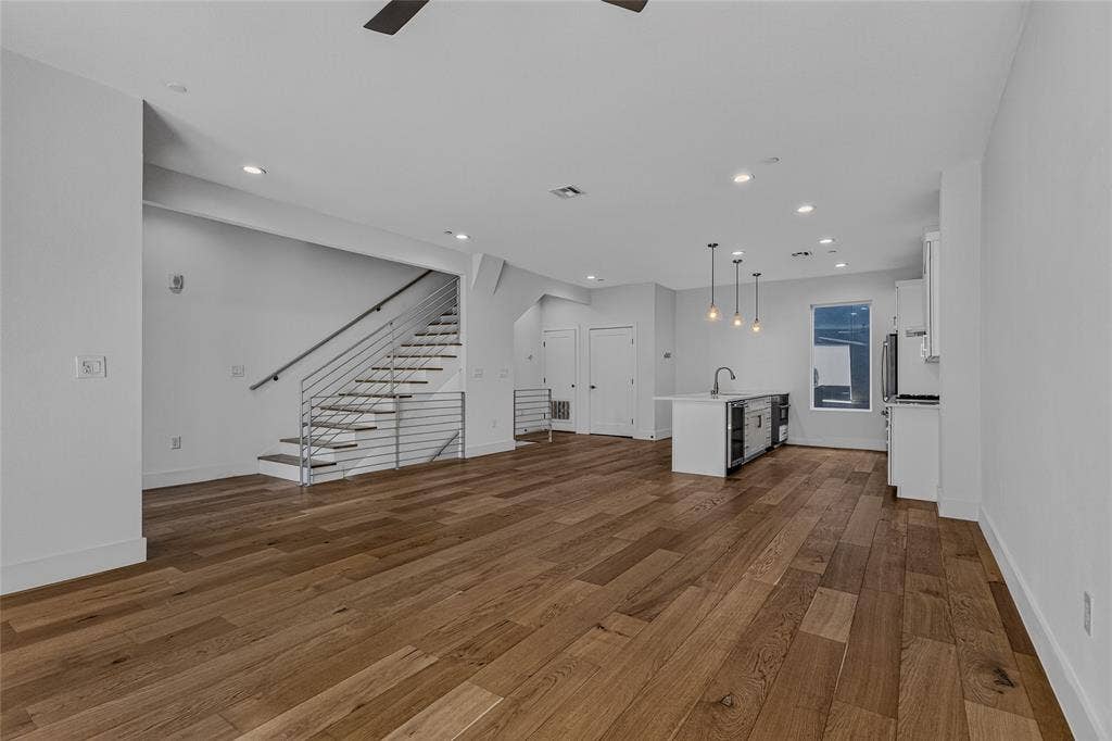 2222 Moser Avenue, #105, Dallas, TX 75206 Open-concept interior featuring wood-finish flooring, recessed lighting, a center kitchen island with a sink, and a staircase with metal horizontal railings