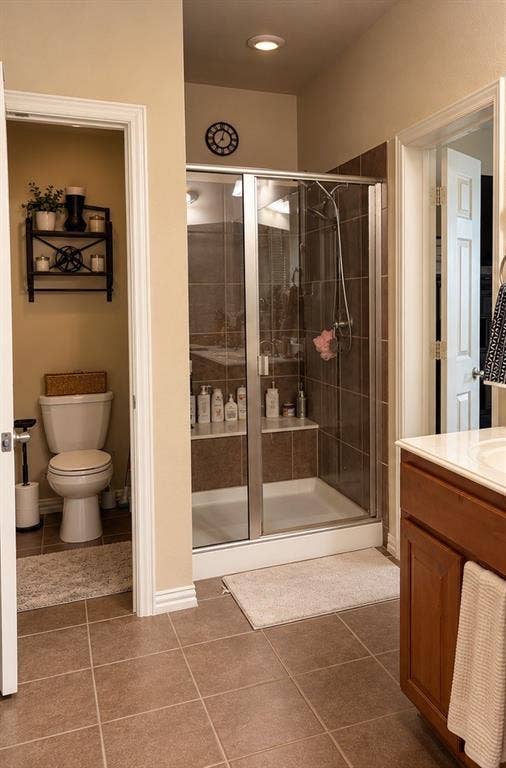 Glass-enclosed shower with tiled surround and built-in bench, wood-finish cabinetry, ceramic floor tiling, and recessed lighting