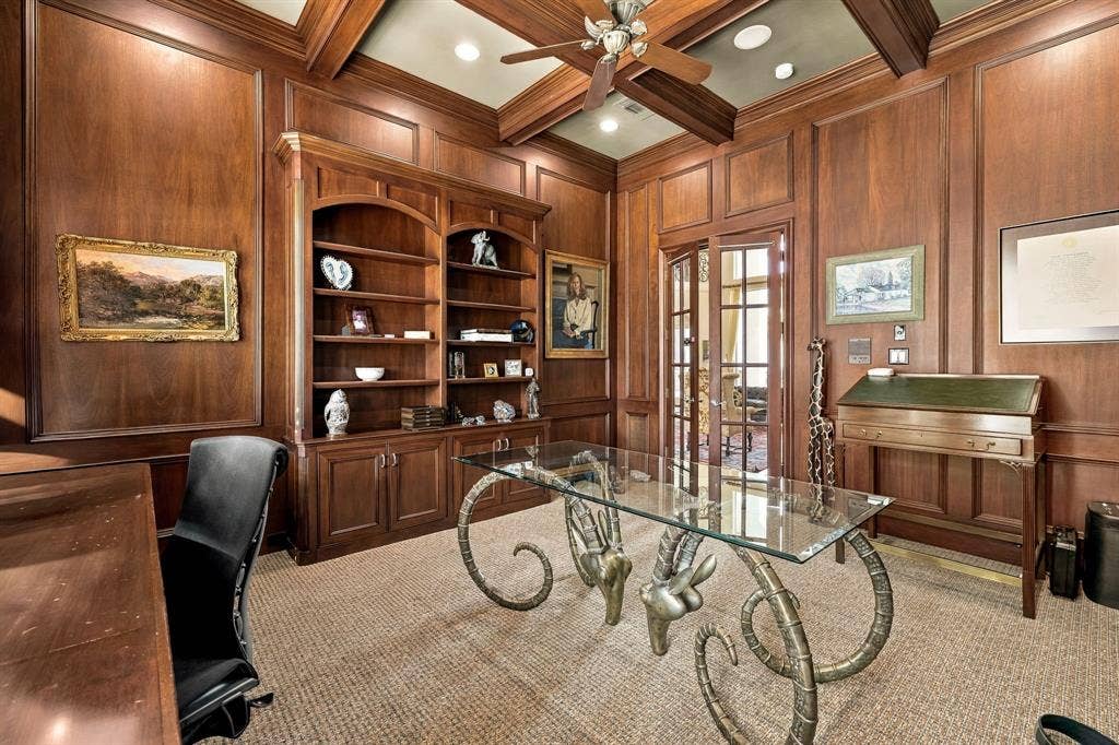 Wood-paneled walls, coffered ceiling, floor-to-ceiling built-in shelving, and French doors
