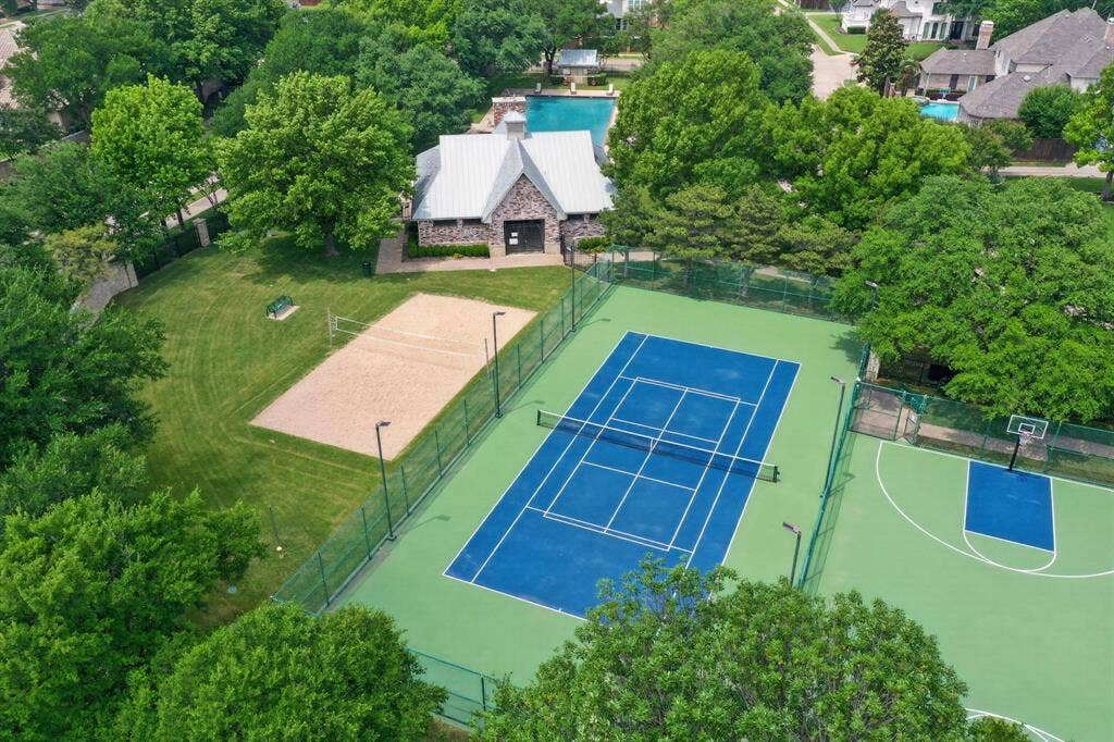 Community recreational facilities featuring a tennis court, a basketball court, a sand volleyball court, and an outdoor swimming pool with a stone-exterior clubhouse