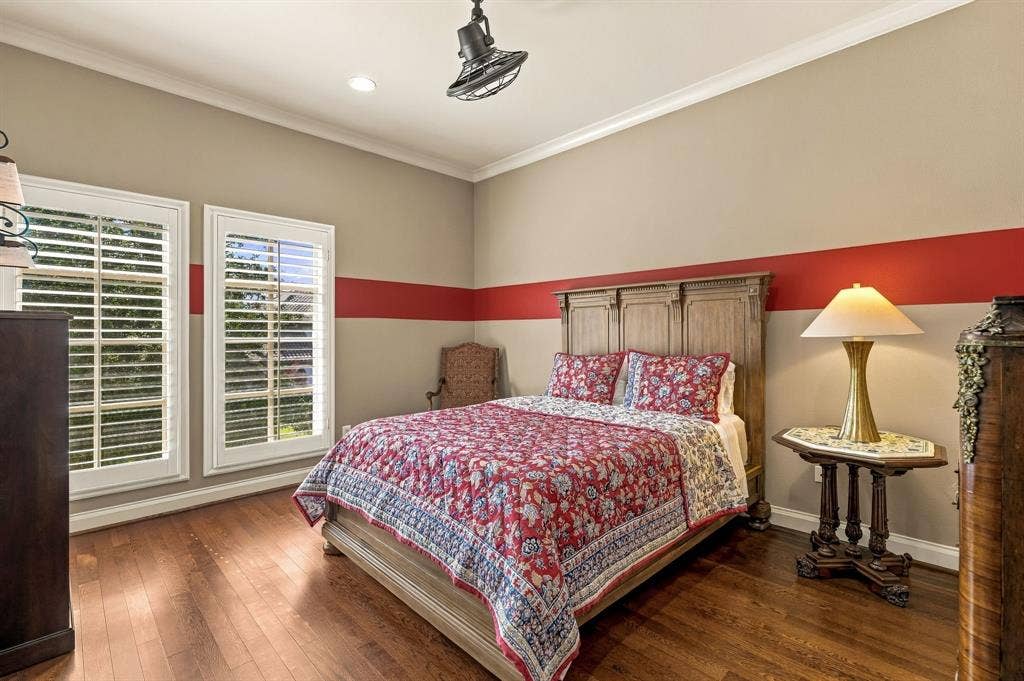 Wood-finish flooring, dual windows with plantation shutters, crown molding, and a ceiling-mounted industrial-style light fixture