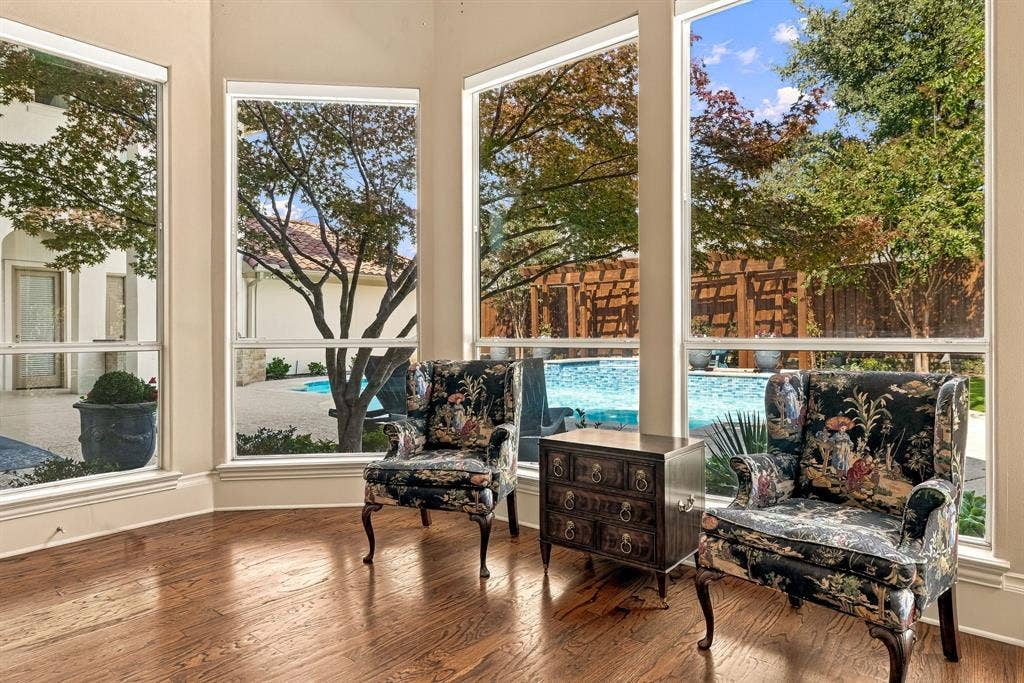 Bay window featuring large-pane glass, wood-finish flooring, and exterior exposure to a swimming pool, patio, and timber pergola