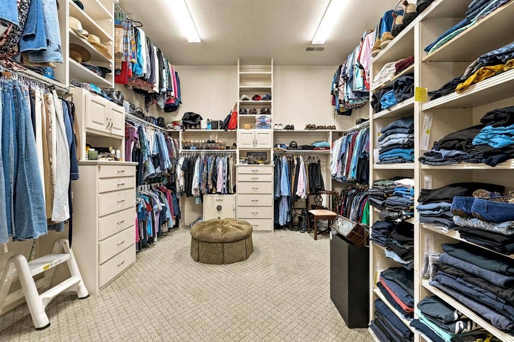 Walk-in closet featuring extensive built-in shelving, custom cabinetry with integrated drawer storage, and full-height hanging rods