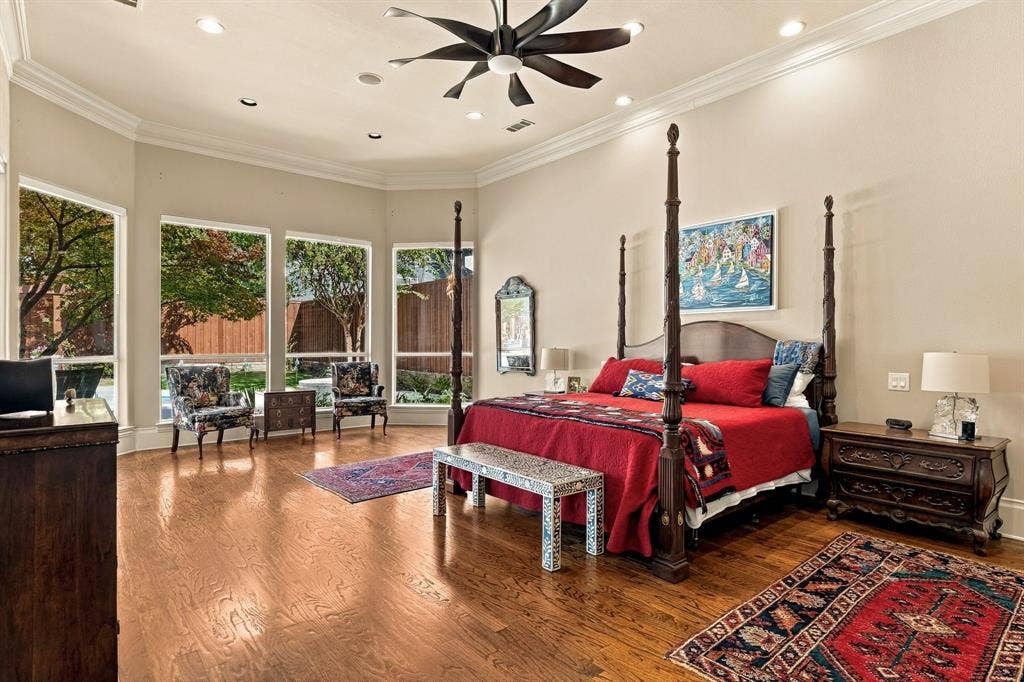 Spacious room featuring wood-finish flooring, recessed lighting, crown molding, a multi-blade ceiling fan, and large windows arranged in a bay configuration