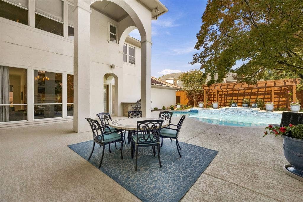 Covered patio featuring architectural arched columns, built-in outdoor kitchen, concrete decking, in-ground swimming pool, and wooden pergola
