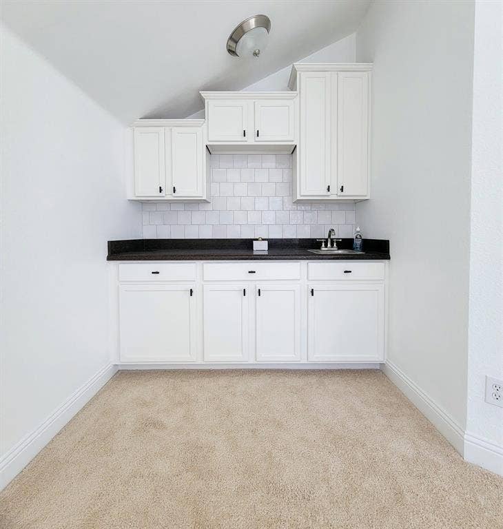 4308 Lee Hutson Drive, Sachse, TX 75048 Built-in cabinetry featuring white Shaker-style doors, dark stone-finish countertops, a subway tile backsplash, and a stainless steel sink with a dual-handle faucet
