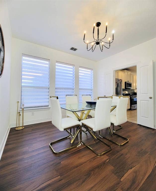 4308 Lee Hutson Drive, Sachse, TX 75048 Dining area featuring wood-finish flooring, a multi-arm chandelier, and three large windows with adjustable blinds