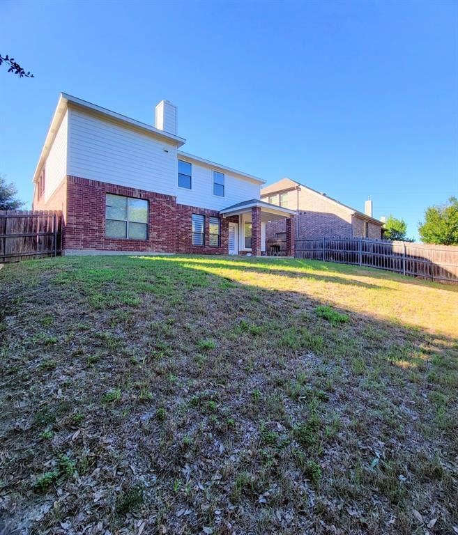 4308 Lee Hutson Drive, Sachse, TX 75048 Two-story exterior featuring a brick and siding facade, covered rear patio, and fenced backyard