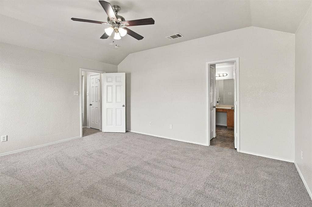 Vaulted ceilings, neutral carpeting, multi-light ceiling fan, and six-panel interior doors