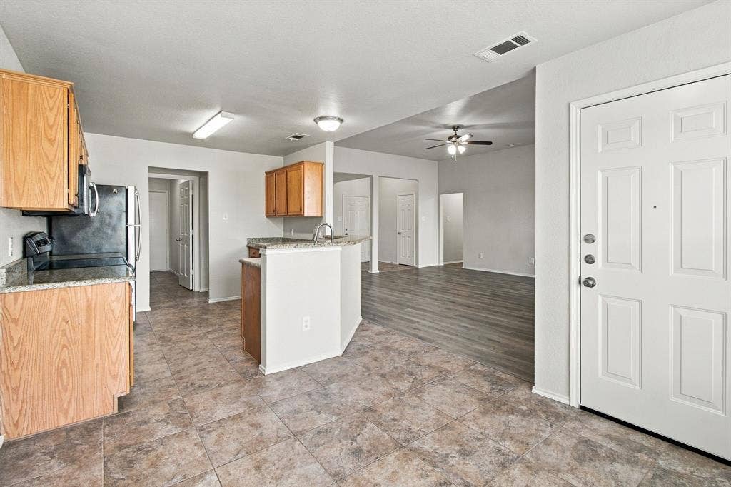 Kitchen featuring wood-finish cabinetry, stone-patterned countertops, tile flooring, and wood-finish flooring in the living area