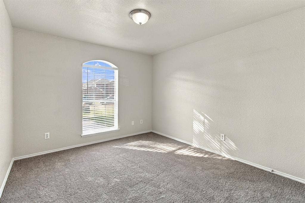 Neutral interior space featuring arched window, wall-to-wall carpeting, and flush-mount ceiling lighting