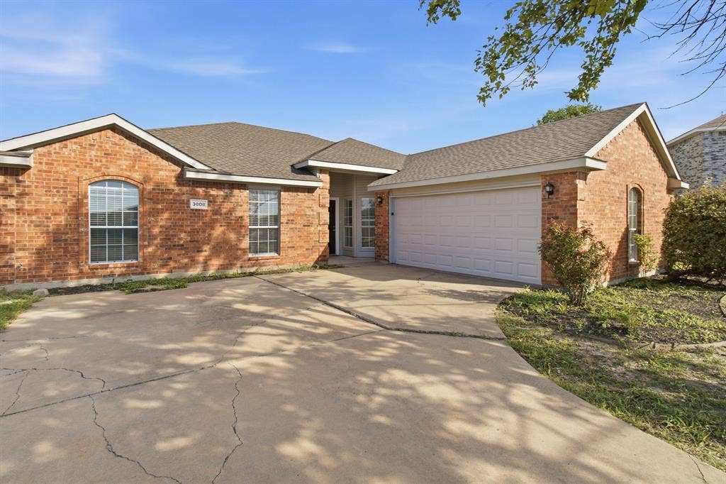 Single-story brick exterior featuring a multi-gabled roofline, concrete driveway, and attached two-car garage