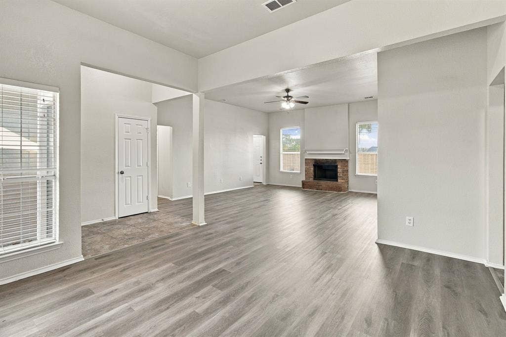 Open concept floor plan featuring wood-finish flooring, a masonry fireplace, vaulted ceilings, and natural light from multiple windows