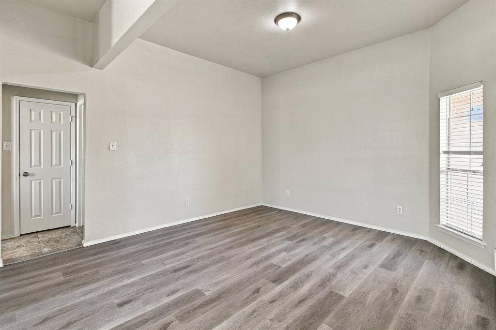 Interior space featuring wood-finish flooring, high ceilings, a flush-mount ceiling light fixture, and a single-panel interior door