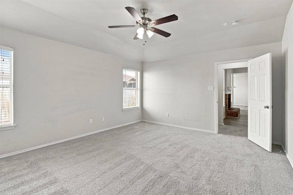 Tray ceiling with a central brushed-nickel ceiling fan, neutral wall-to-wall carpeting, and double-hung windows
