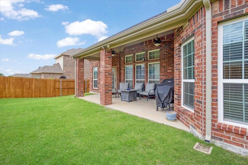 319 Westphalian Drive, Celina, TX 75009 Expansive green lawn with a covered patio featuring brick columns, concrete flooring, and multiple ceiling fans