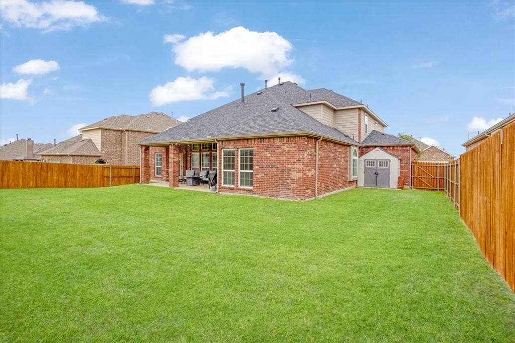 319 Westphalian Drive, Celina, TX 75009 Expansive backyard featuring a lush lawn, privacy fencing, and a covered patio