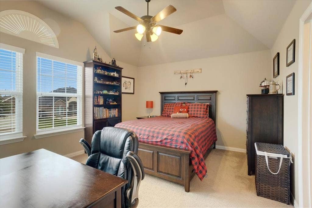319 Westphalian Drive, Celina, TX 75009 Vaulted ceiling bedroom featuring two windows with horizontal blinds, an arched transom window, a ceiling fan with integrated lighting, and neutral wall paint