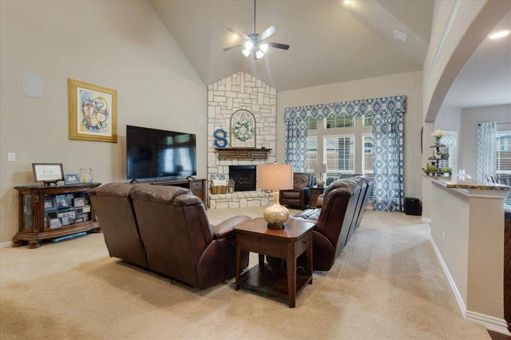 319 Westphalian Drive, Celina, TX 75009 Living area featuring a stone fireplace, vaulted ceiling with a ceiling fan, and large windows