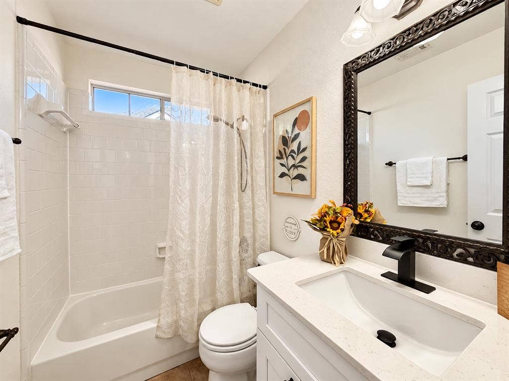 7514 Naples Lane, Frisco, TX 75035 Bathroom featuring a vanity with a white countertop and rectangular undermount sink, matte black faucet, framed mirror, and a tub-shower combination with white wall tile