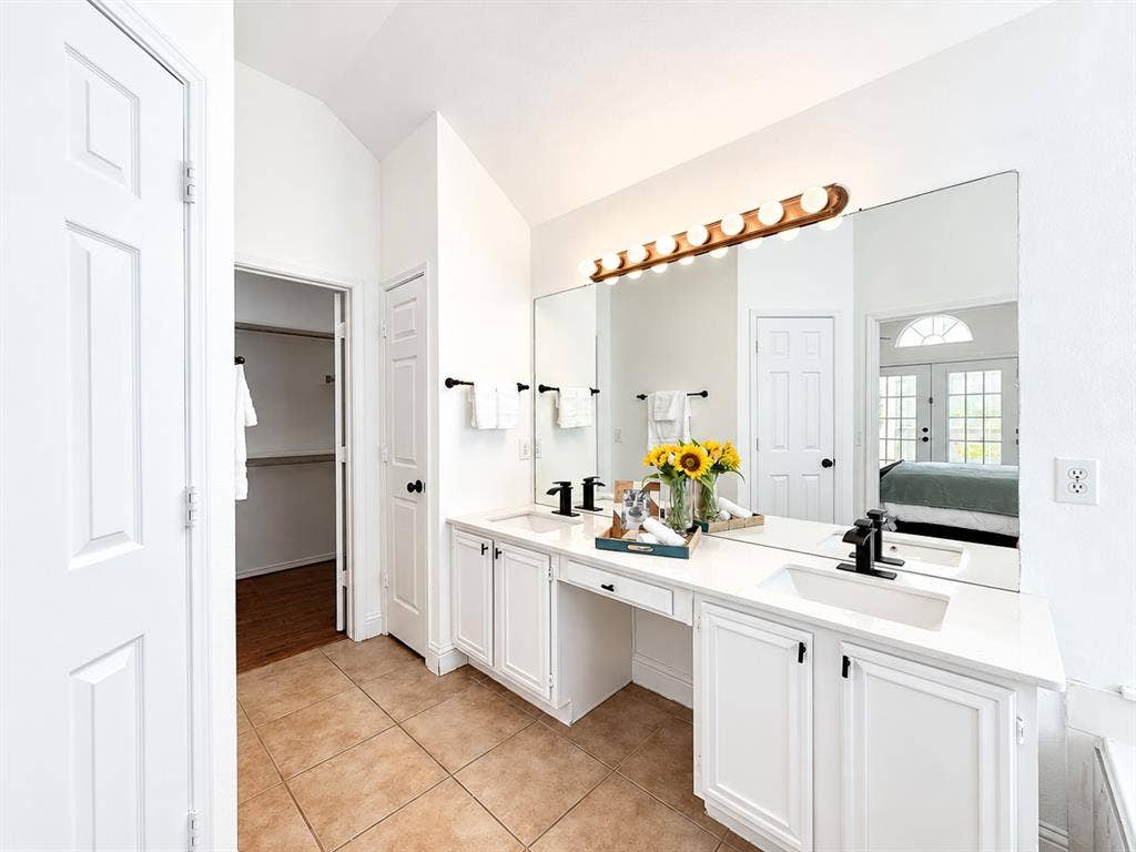 7514 Naples Lane, Frisco, TX 75035 Dual-sink vanity with white cabinetry, expansive countertop, matte black fixtures, and a multi-bulb vanity light