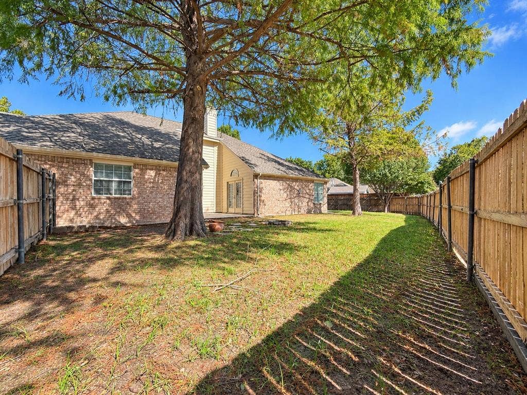 7514 Naples Lane, Frisco, TX 75035 Spacious backyard featuring masonry exterior siding, mature trees, and wooden privacy fencing