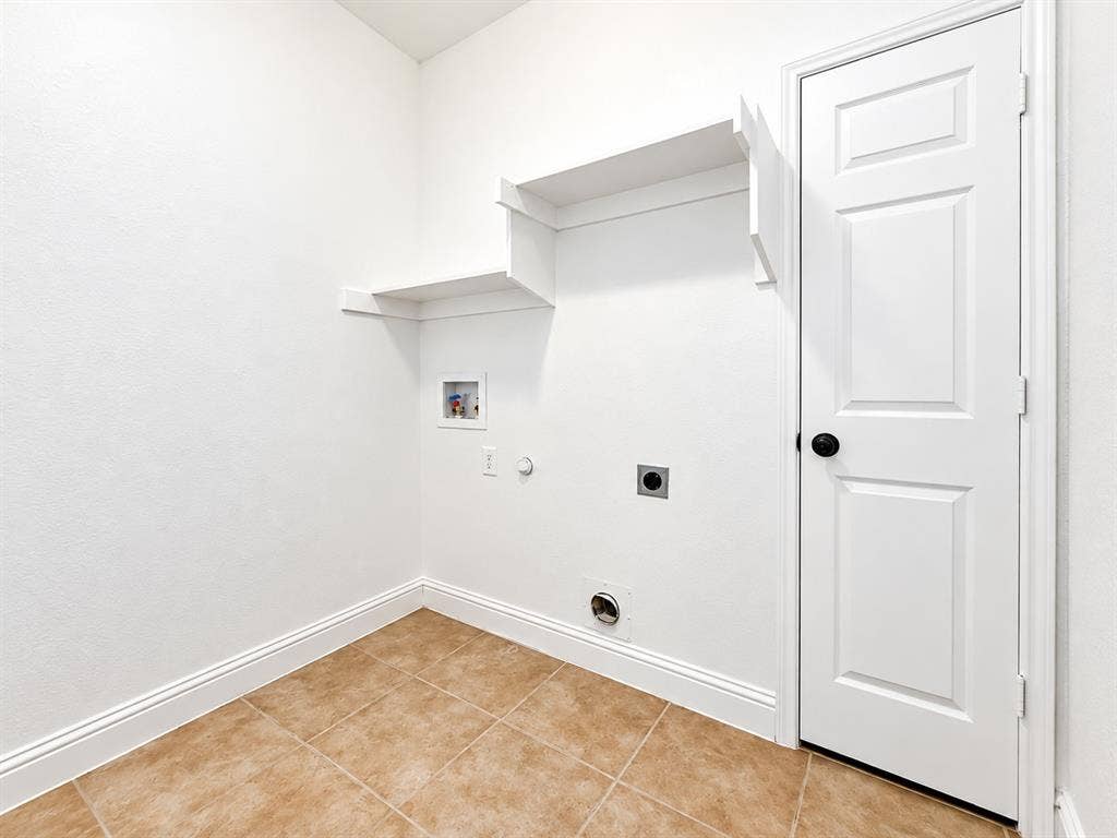7514 Naples Lane, Frisco, TX 75035 Utility area featuring ceramic tile flooring, built-in wall shelving, and a six-panel door with matte black hardware