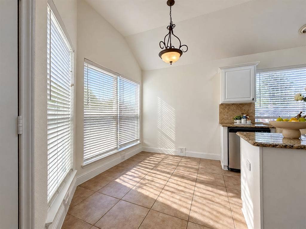 7514 Naples Lane, Frisco, TX 75035 Vaulted ceilings, expansive windows with horizontal blinds, tiled flooring, ornate pendant lighting, and stone-finish countertops with tile backsplash