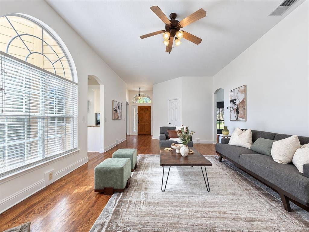 7514 Naples Lane, Frisco, TX 75035 Living area featuring wood-finish flooring, a large arched window with horizontal blinds, a vaulted ceiling, and a ceiling fan with integrated light fixtures