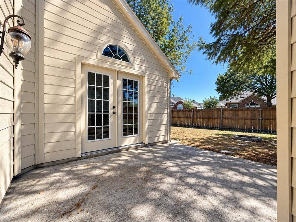 7514 Naples Lane, Frisco, TX 75035 Concrete patio featuring double French glass doors, a semi-circular transom window, exterior lantern-style wall lighting, and wood-toned lap siding