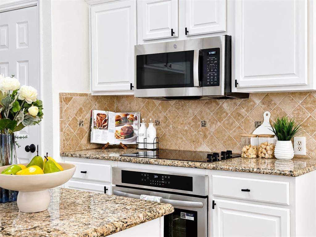 7514 Naples Lane, Frisco, TX 75035 Kitchen featuring white shaker-style cabinetry, stone countertops, a diagonal-set stone tile backsplash, stainless steel built-in microwave, and a glass-top electric range