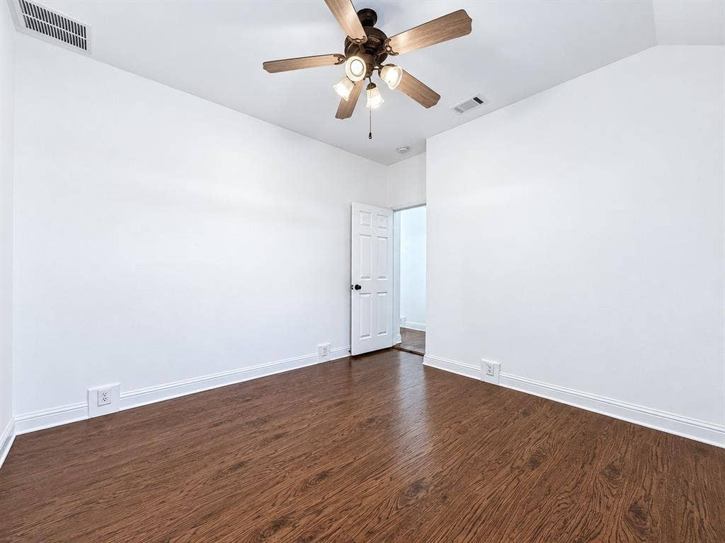 7514 Naples Lane, Frisco, TX 75035 Room featuring wood-finish flooring, a multi-blade ceiling fan with integrated lighting, and a six-panel interior door