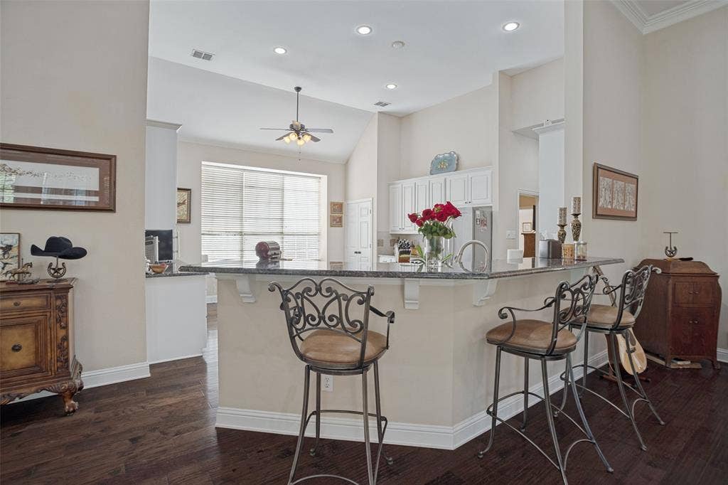 701 Crabapple Way, McKinney, TX 75072 Interior featuring dark wood-finish flooring, vaulted ceilings with recessed lighting, and a raised countertop peninsula with decorative corbels and a sink Breakfast bar