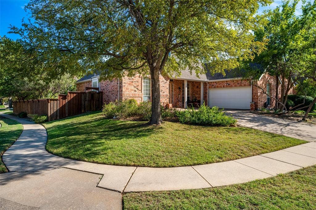 701 Crabapple Way, McKinney, TX 75072 Brick exterior with a covered entryway, attached garage, concrete driveway, and mature landscaping