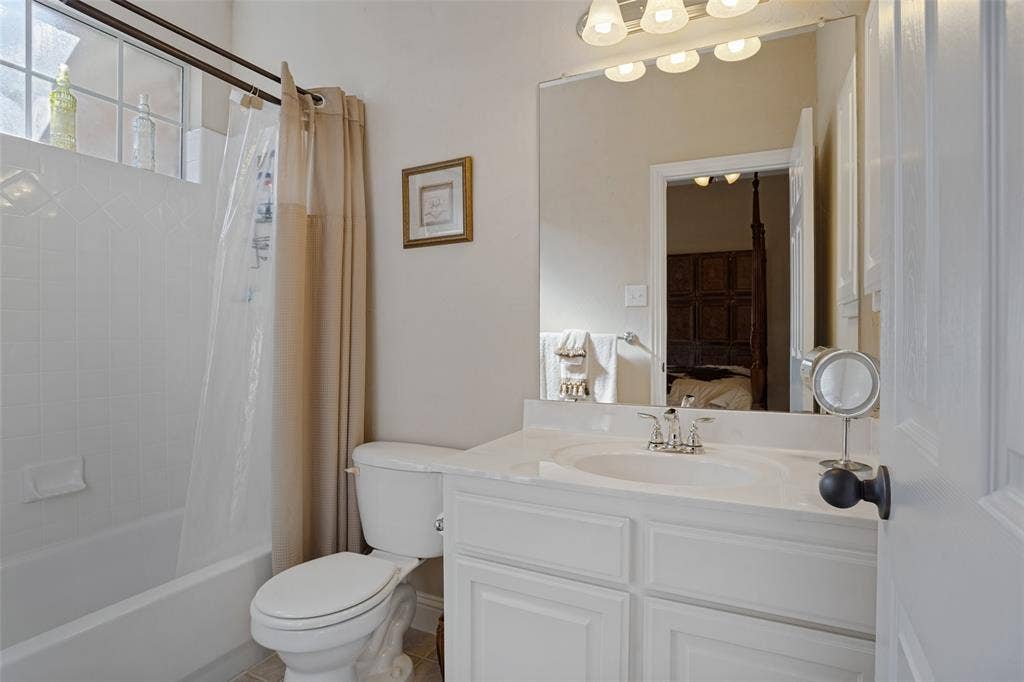 701 Crabapple Way, McKinney, TX 75072 Bathroom featuring a vanity with an integrated basin, a large wall-mounted mirror, multi-bulb overhead lighting, a shower-tub combination with tile surround, and an upper transom window
