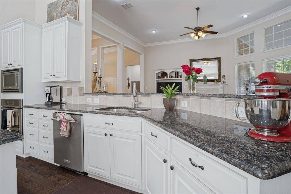 701 Crabapple Way, McKinney, TX 75072 Kitchen featuring white shaker-style cabinetry, dark stone countertops, stainless steel dishwasher, built-in microwave and wall oven, and wood-finish flooring