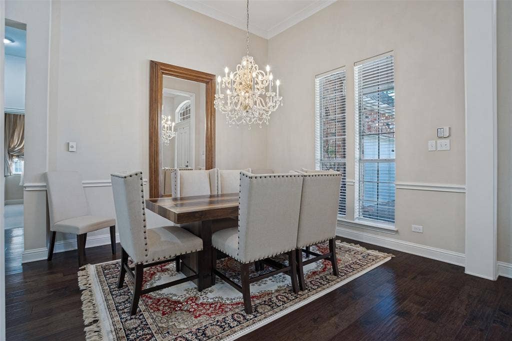 701 Crabapple Way, McKinney, TX 75072 Dining area featuring wood-finish flooring, a decorative crystal chandelier, chair rail molding, and tall windows with horizontal blinds