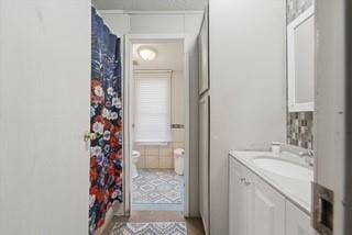 866 Old Church Rd, Waxahachie, TX 75165 Bathroom featuring a vanity with integrated sink, stone-finish countertop, decorative tile backsplash, and full-height built-in storage cabinetry