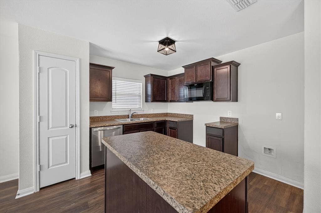 14276 Greenhaw Lane, Dallas, TX 75253 Kitchen featuring dark-toned cabinetry, a center island with countertop, stainless steel dishwasher, integrated microwave, and wood-finish flooring