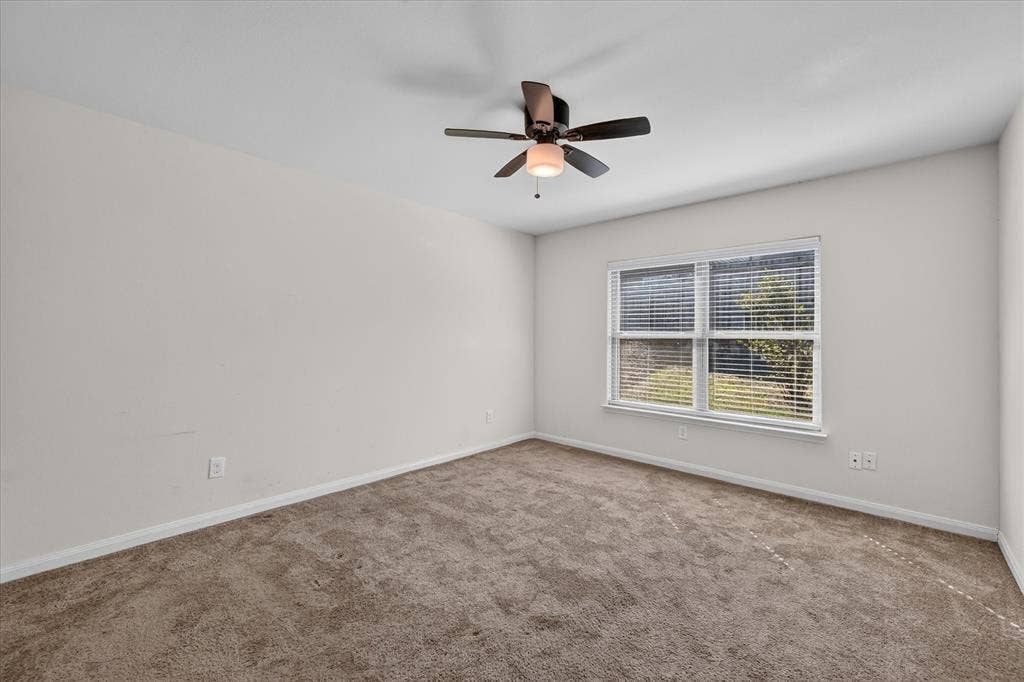14276 Greenhaw Lane, Dallas, TX 75253 Neutral-toned wall interior featuring plush wall-to-wall carpeting, a multi-blade ceiling fan with an integrated light fixture, and a dual-pane window