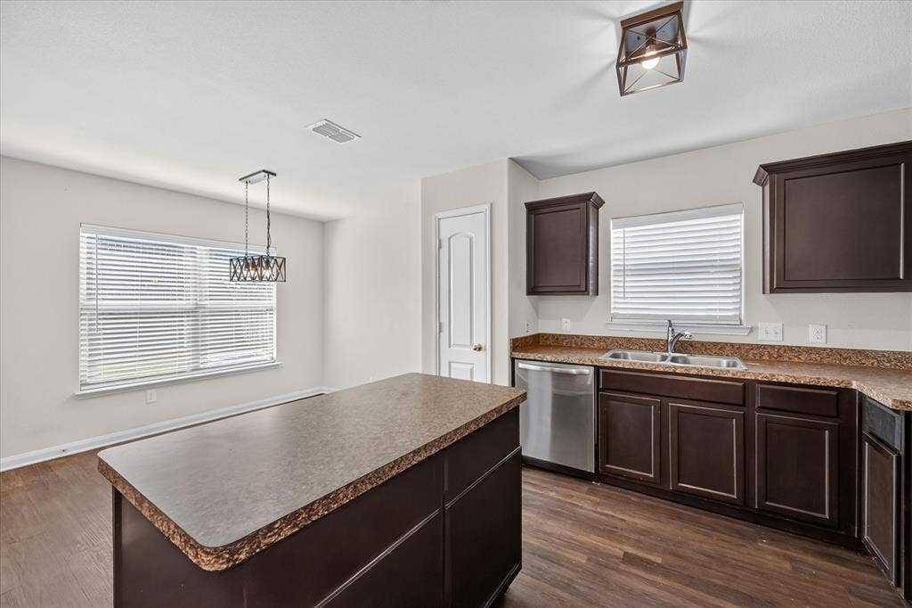 14276 Greenhaw Lane, Dallas, TX 75253 Kitchen featuring dark cabinetry, expansive countertops, a central island, stainless steel dishwasher, and wood-finish flooring