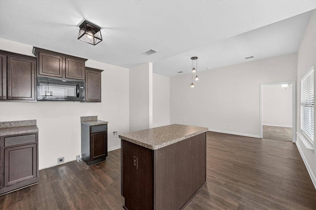 14276 Greenhaw Lane, Dallas, TX 75253 Kitchen featuring dark-finish cabinetry, stone-texture countertops, wood-finish flooring, a center island, and overhead pendant lighting
