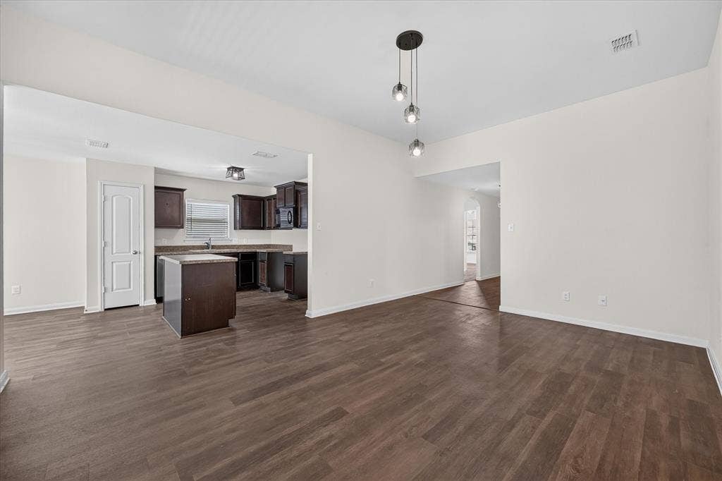 14276 Greenhaw Lane, Dallas, TX 75253 Open-concept living space with wood-finish flooring, three-globe pendant lighting, dark wood-finish cabinetry, center kitchen island, and neutral wall tones